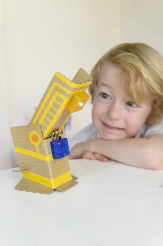 Happy child playing with the finished product from our 4M TechCraft Paper Circuit Science